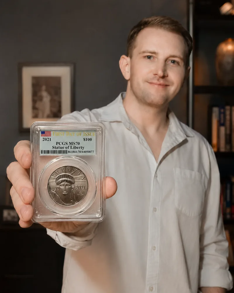 Raymond J. Kraft, founder of CounterMint, holding a slabbed 2021 Statue of Liberty platinum coin toward the camera.